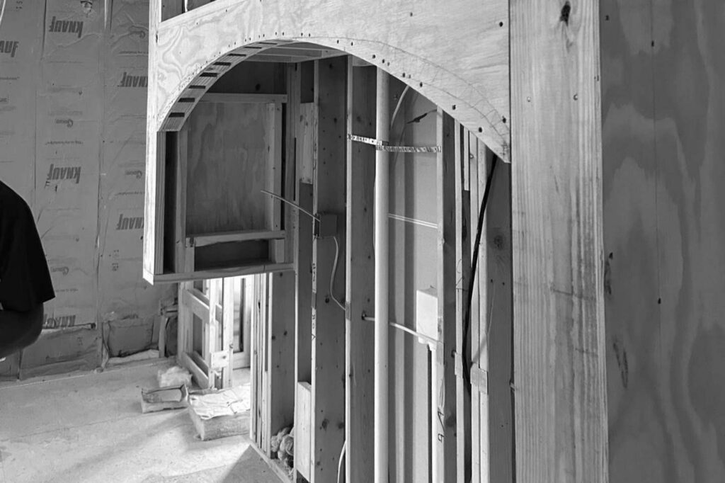 Exposed wood framing forms the kitchen hood arch and side recesses during construction.