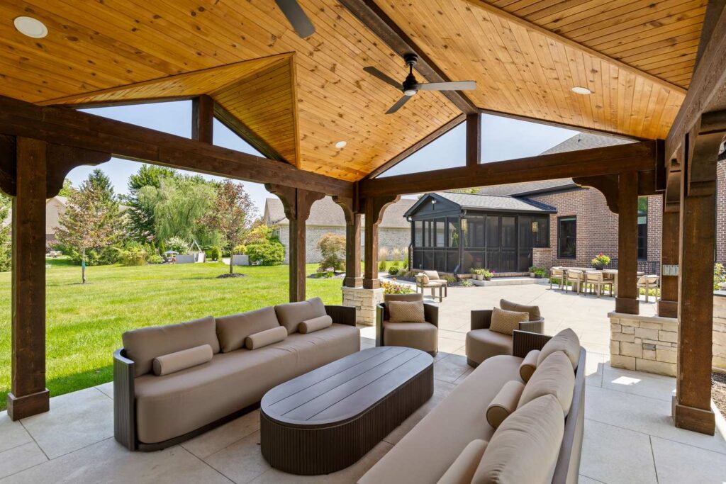 View from the pavilion seating across the patio toward the screened porch and brick Carmel home.