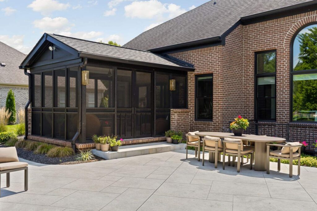 Updated screened porch beside an outdoor dining table on the patterned concrete patio in Carmel.