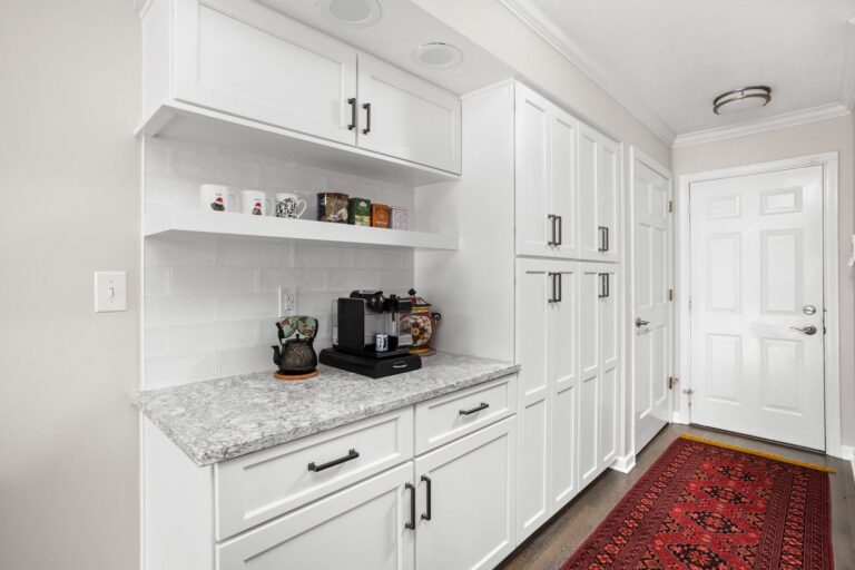 White kitchen cabinetry with a built-in coffee station, floating shelf and tall storage cabinets in Indianapolis.