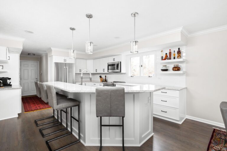 Finished Indianapolis kitchen with white cabinets, an expanded island with seating and light quartz countertops.