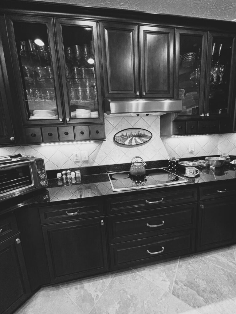 Before the makeover, the Westfield kitchen cooktop wall had stained cabinetry, dark countertops and diagonal tile backsplash.