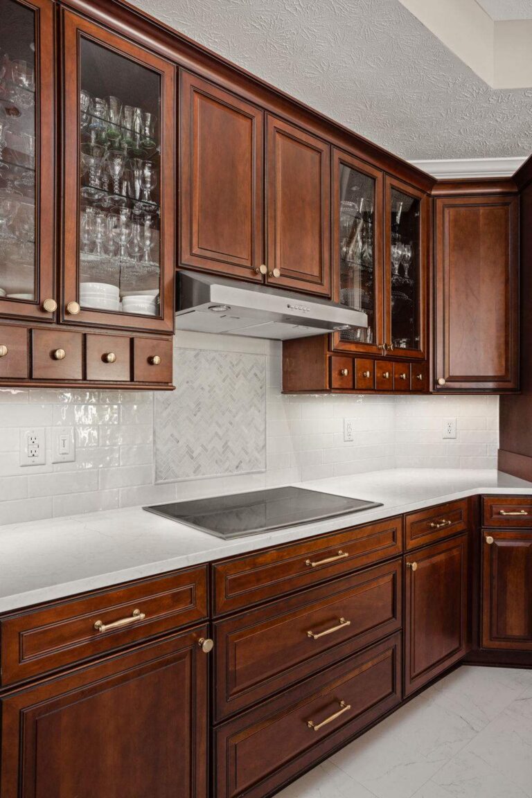 Existing stained kitchen cabinetry in the finished Westfield kitchen with new Honey Bronze hardware, white quartz counters and tile backsplash.