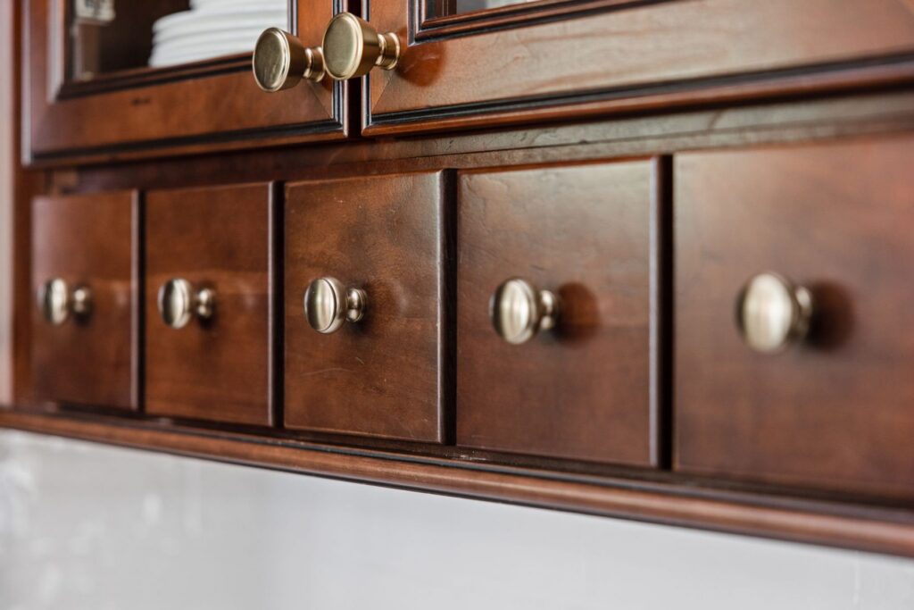 Close-up of Honey Bronze knobs and pulls on the retained stained kitchen cabinetry.